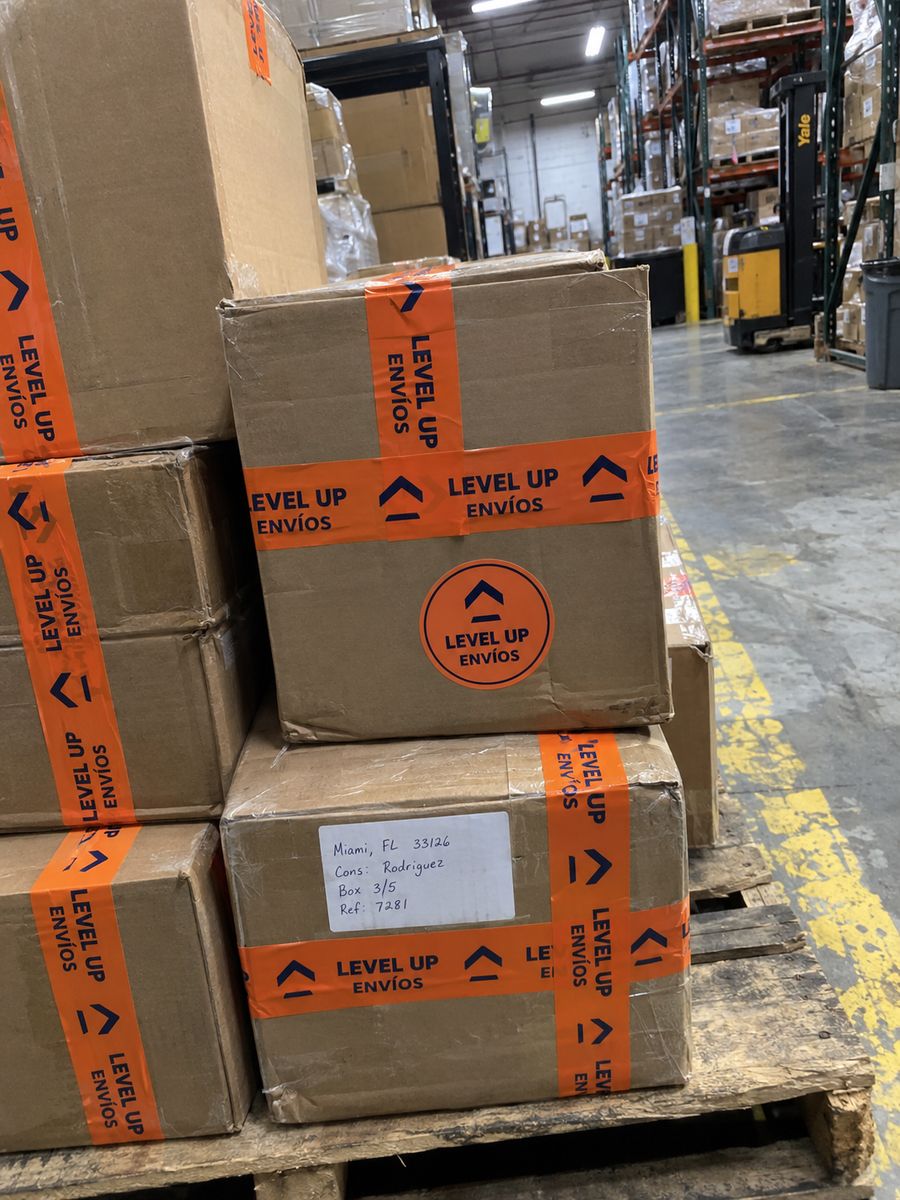 Cajas con cinta Level Up Envíos sobre una paleta en el almacén